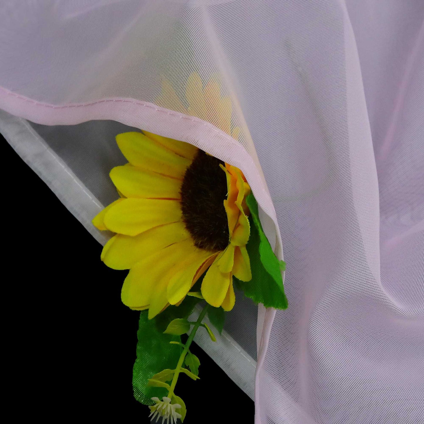 Detail des rosafarbenen Stoffs mit halbdurchsichtiger Konstruktion, darunter sind die Sonnenblumen zu sehen, die Mikro-Mesh-Konstruktion und die rosafarbene Verkleidung.