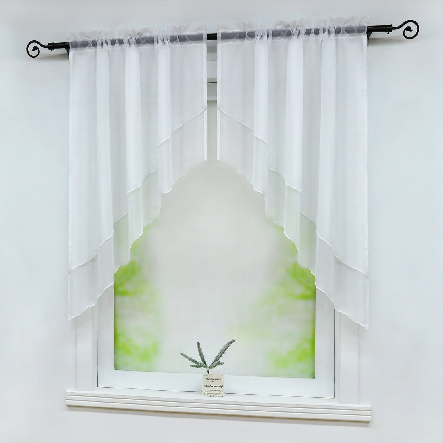Seitliche Ansicht eines Fensters mit weißen, halbtransparenten Vorhängen, die symmetrisch diagonal geschnitten sind. Eine kleine grüne Pflanze steht dekorativ auf der Fensterbank vor einem weichen, grünen Hintergrund.