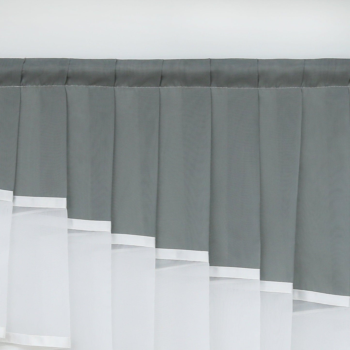 Dies ist ein Ausschnitt eines Fensters mit einem eleganten Vorhang. Der obere Teil besteht aus dunkelgrauem Stoff mit gleichmäßigen Falten, während der untere Teil nahtlos mit weißem, transparentem Stoff verbunden ist. Der weiße Stoff hat dekorative Kanten und verleiht dem Vorhang ein ansprechendes, dekoratives Aussehen. Perfekt für die Fensterdekoration im Wohnbereich.
