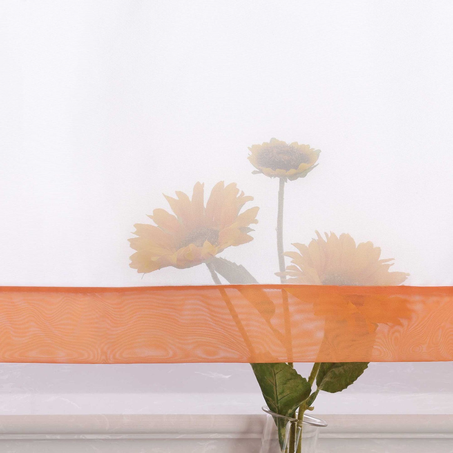 Die Unterkante des Vorhangs wird im Detail gezeigt, mit einer leichten Transparenz, die den Blick auf eine Büschel von Sonnenblumen im Hintergrund freigibt. Die sanfte Durchsicht des Vorhangs lässt das natürliche Licht durch und schafft eine harmonische Atmosphäre, während die Blumen dezent hervorblitzen.
