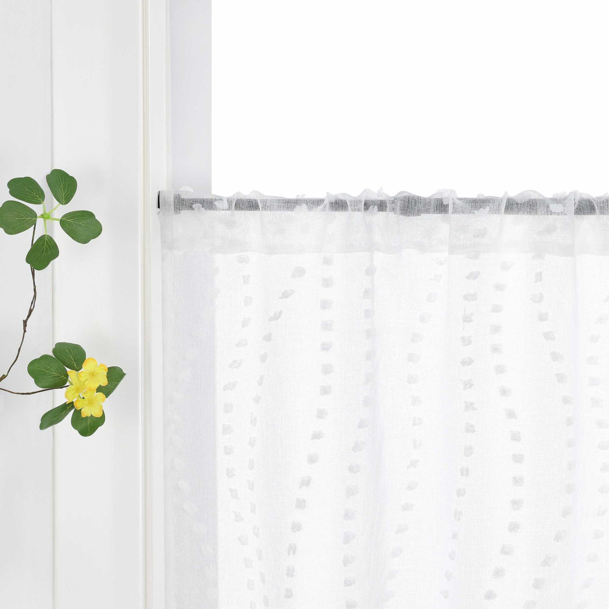 Die weiße Gardine mit dem 3D-Punktemuster hängt an einem Fenster, wobei die Aufhängung über die Schlaufen am Vorhangstab sichtbar ist. Das punktuelle Design der Gardine kommt klar zur Geltung und fügt dem Raum eine elegante Textur hinzu. Grüne Pflanzen am Fenster ergänzen das harmonische Gesamtbild und bringen Frische ins Zimmer.