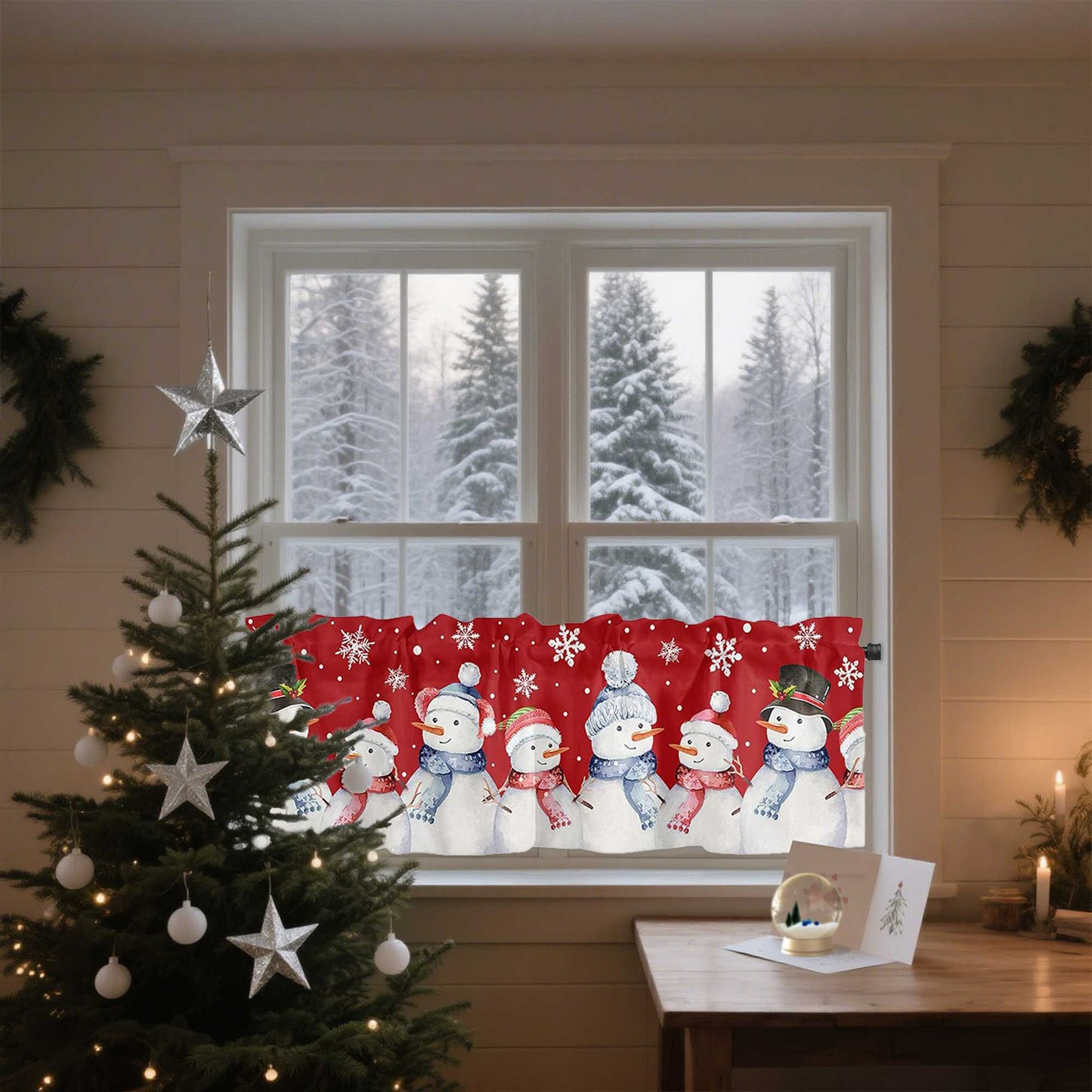 Das Bild zeigt ein gemütliches Wohnzimmer mit einem festlich dekorierten Fenster. Der rote Vorhang ist mit fröhlichen Schneemännern verziert, die in blauen Schals und Hüten abgebildet sind, umgeben von weißen Schneeflocken. Durch das Fenster ist eine verschneite Winterlandschaft mit hohen Bäumen zu sehen. Im Vordergrund steht ein geschmückter Weihnachtsbaum mit silbernen Sternen und Kugeln, und auf dem Tisch liegt eine kleine Weihnachtskarte.