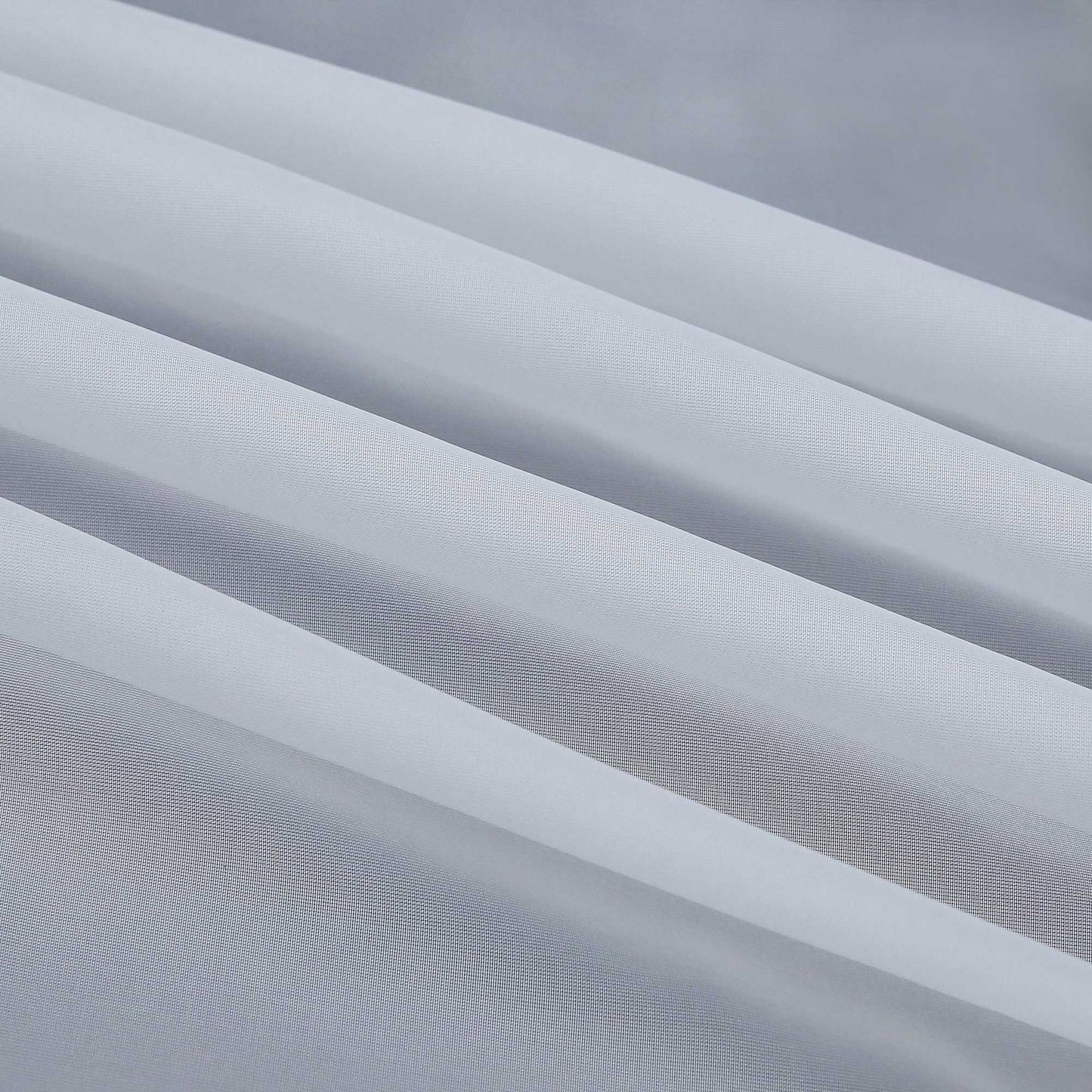 Detail eines grauen, halbtransparenten Gardinenstoffs mit deutlich sichtbarem Saum und sauber gefalteten Kanten. Die feine Struktur des Stoffes lässt das Licht sanft eindringen.