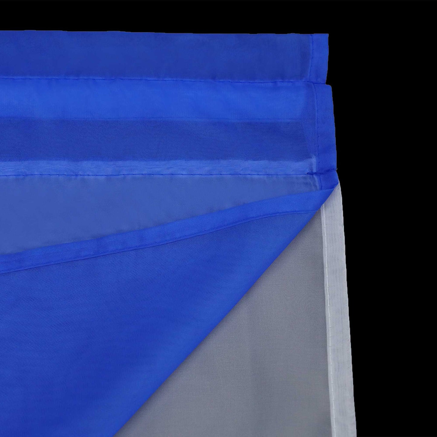 Detail eines marineblauen, halbtransparenten Gardinenstoffs mit sauber gefalteten Kanten. Die umgeschlagenen Kanten sind sauber und fein gepresst, und die oberste Lage des marineblauen Gardinenstoffs ist gegenüber dem darunter liegenden weißen Stoff halbdurchlässig.