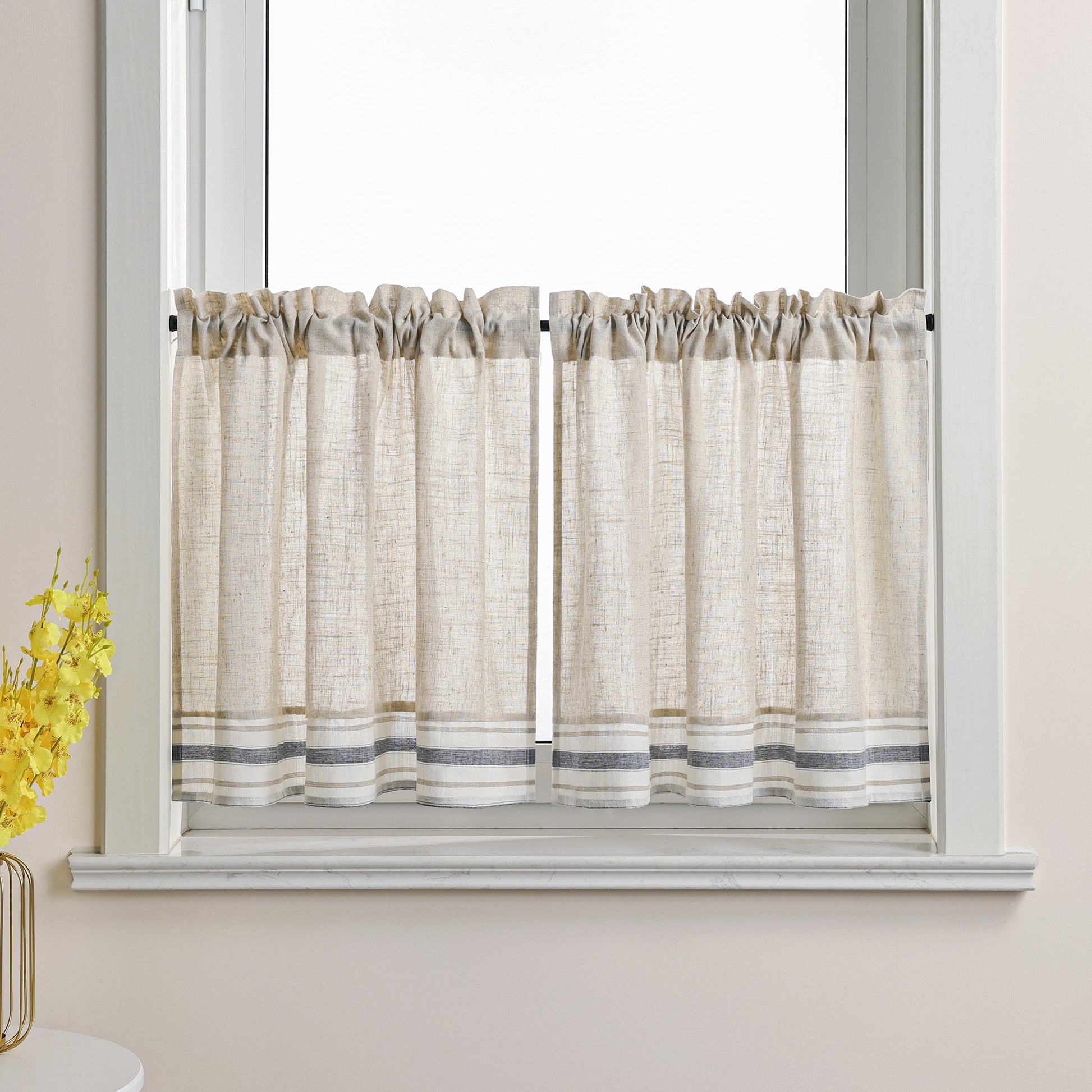 Dies ist eine Gardine im Landhausstil, die am Fenster angebracht ist. Der Hauptstoff ist cremeweiß mit einer Leinenstruktur. Der untere Rand ist mit grauen und weißen Streifen verziert. Diese Scheibengardinen im Landhausstil verleihen Ihrem Raum ein natürliches und schlichtes Ambiente. Sie passen gut zu verschiedenen Einrichtungsstilen wie skandinavischem oder japanischem Design und sorgen für sanftes Licht sowie eine warme, einladende Atmosphäre.