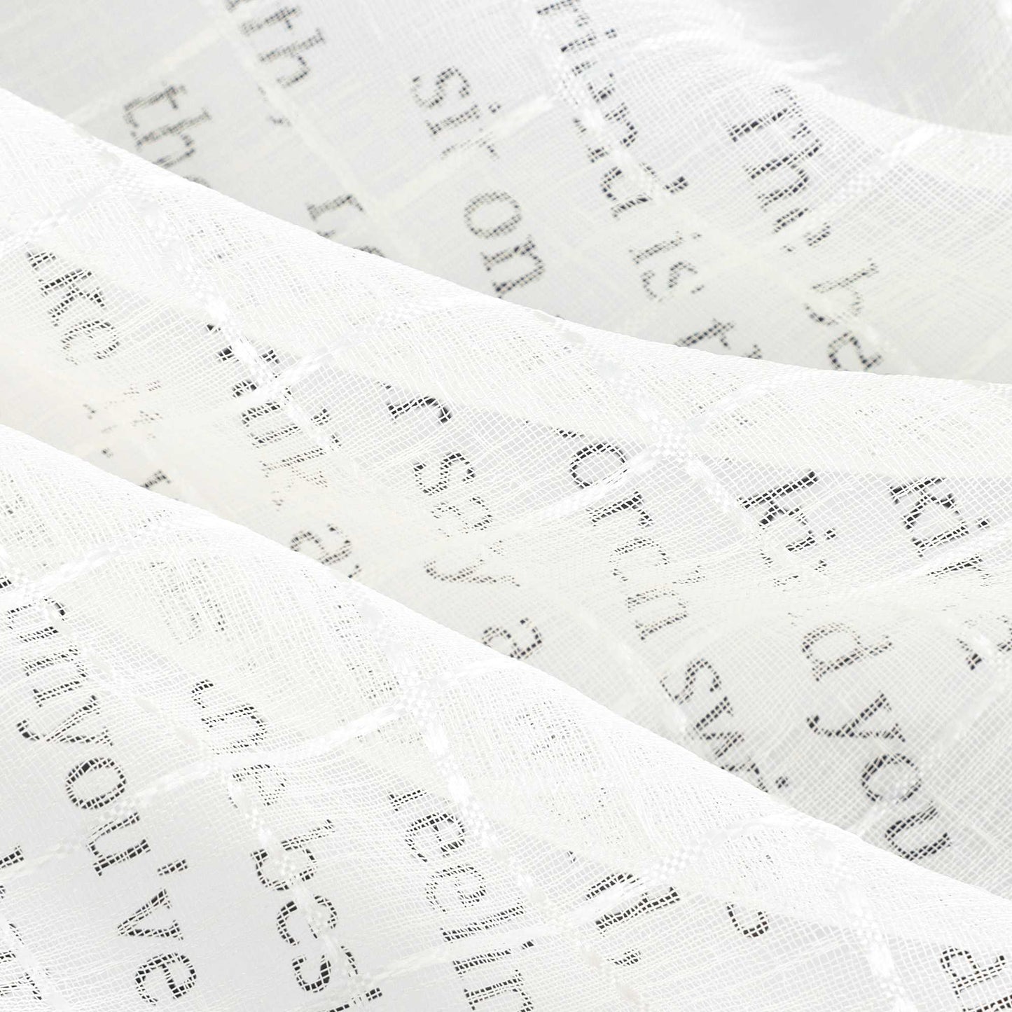 Der cremefarbene, transparente Vorhangstoff zeigt eine regelmäßige Karostruktur. Gedruckter Text im Hintergrund ist klar lesbar, was die hohe Lichtdurchlässigkeit des Materials unterstreicht. Die weich verlaufenden Stofffalten verstärken die luftige Optik.