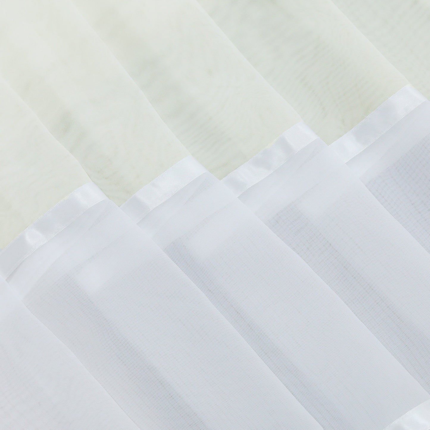 Dies ist eine Detailaufnahme des Schleiermaterials am Vorhang. Der Stoff ist leicht und transparent, mit einem weißen Dekorband am Rand. Der obere Teil verbindet sich mit dem cremeweißen Stoff und zeigt eine feine Verarbeitung sowie eine schöne Schichtung, die die Fensterdekoration optisch aufwertet.