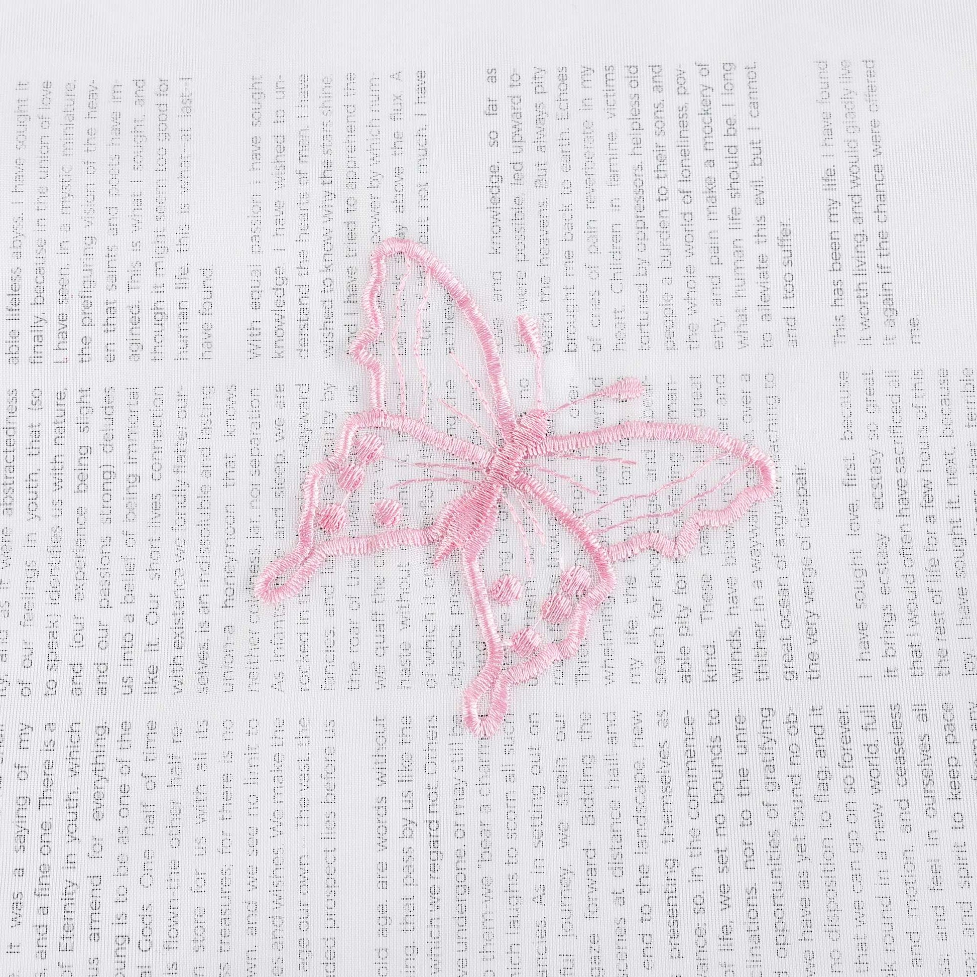 Nahaufnahme einer rosa Schmetterlingsstickerei, die auf einem transparenten weißen Stoff flach ausgebreitet liegt. Die rosa Schmetterlinge sind sorgfältig in das Gewebe eingearbeitet.