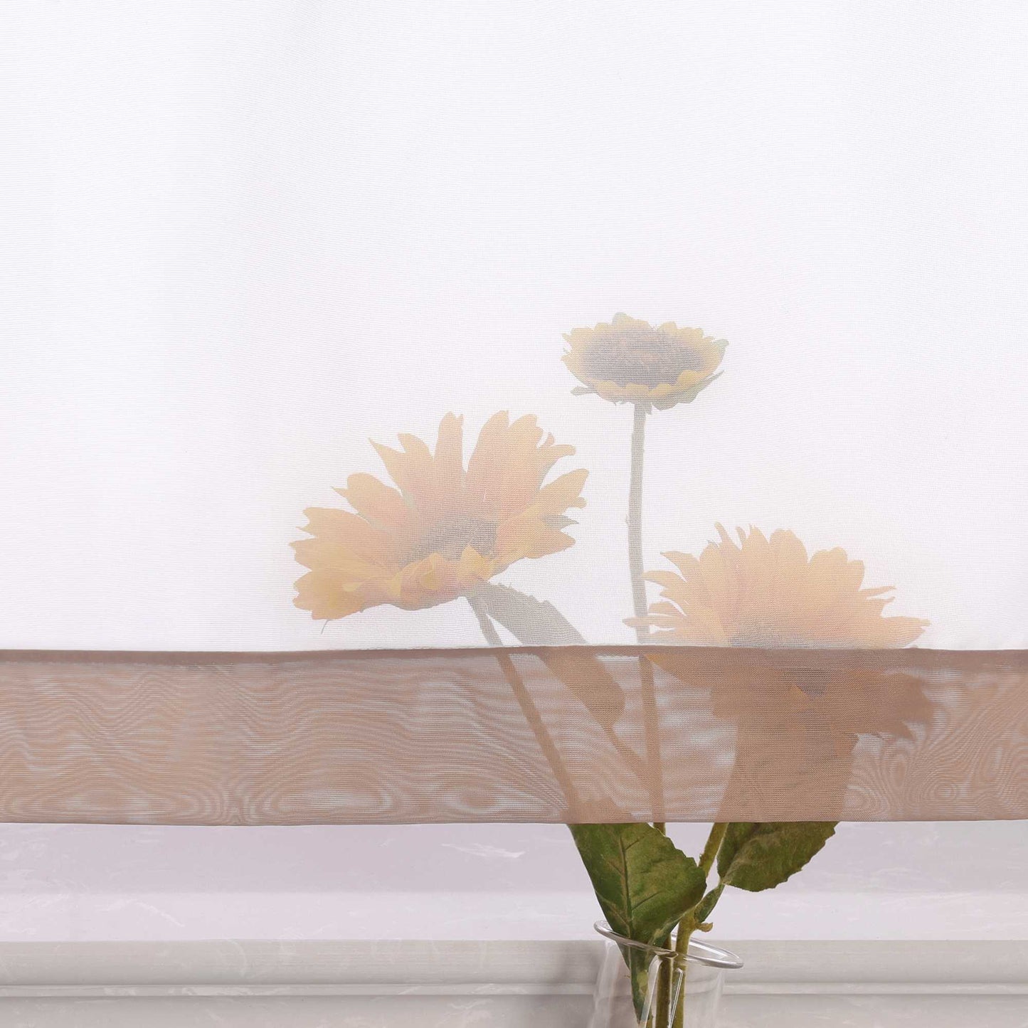 Die Unterkante des Vorhangs wird im Detail gezeigt, mit einer leichten Transparenz, die den Blick auf eine Büschel von Sonnenblumen im Hintergrund freigibt. Die sanfte Durchsicht des Vorhangs lässt das natürliche Licht durch und schafft eine harmonische Atmosphäre, während die Blumen dezent hervorblitzen.