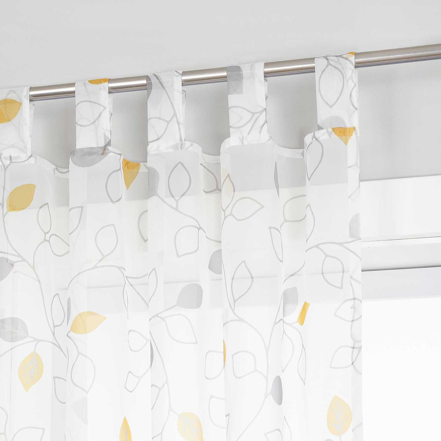 Dies ist ein weißer Voile-Vorhang mit grünen und grauen Blättermustern. Der Vorhang hängt an einer Metallstange vor dem Fenster und wird von grünen Pflanzen und minimalistischen weißen Dekorationsstücken umrahmt. Der Voile bietet eine gute Lichtdurchlässigkeit und sorgt für sanftes Licht im Raum. Das frische Muster verleiht dem Raum eine natürliche Atmosphäre und ist ideal für Schlafzimmer, Wohnzimmer und andere Räume, um die Schönheit und den Komfort des Zuhauses zu steigern.